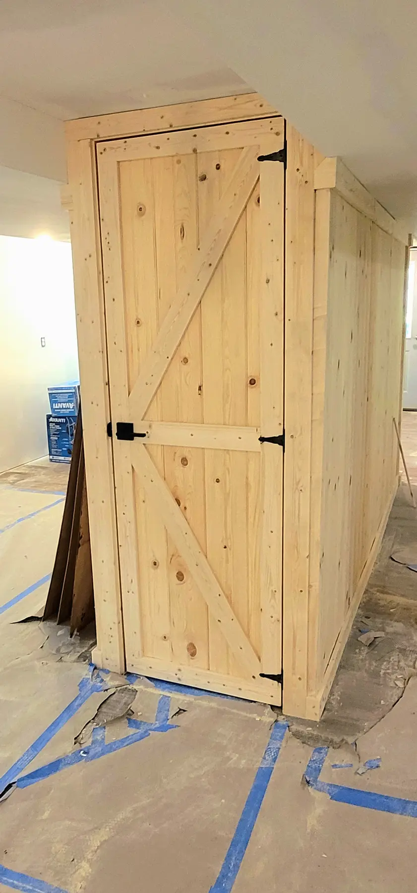 Finished raw-pine K-brace door enclosing the under-stair storage closet