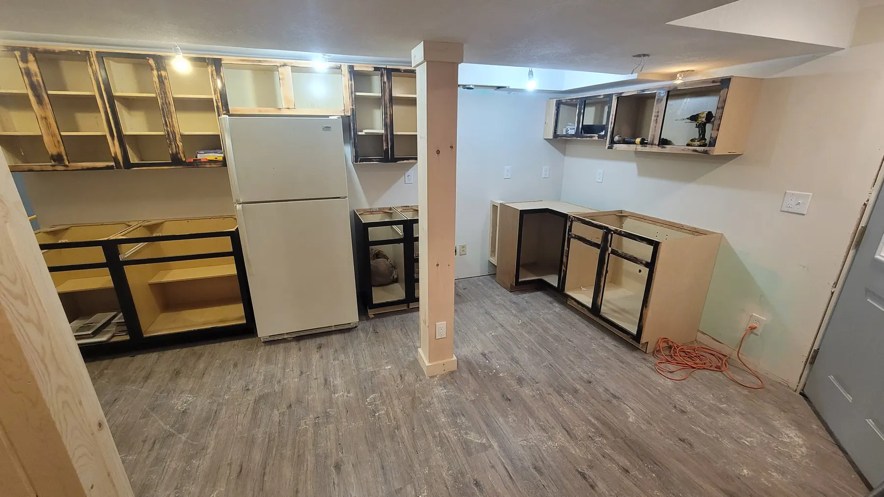 Repurposed kitchenette cabinet boxes being hung and leveled, mid-installation, before paint and door installation