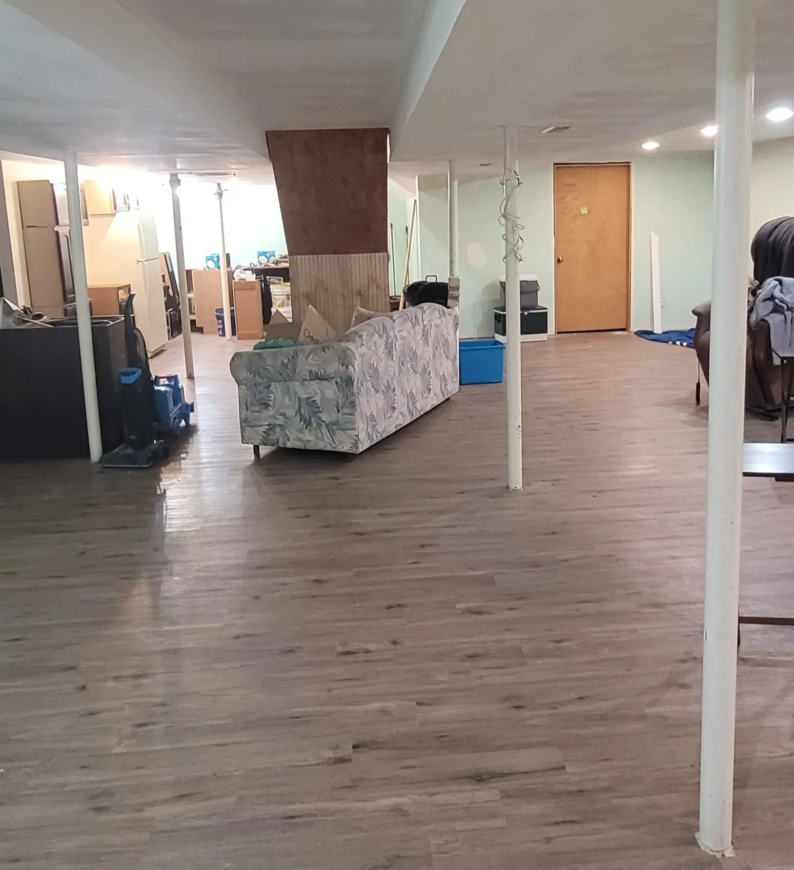 Unfinished basement before the remodel, with bare metal support poles