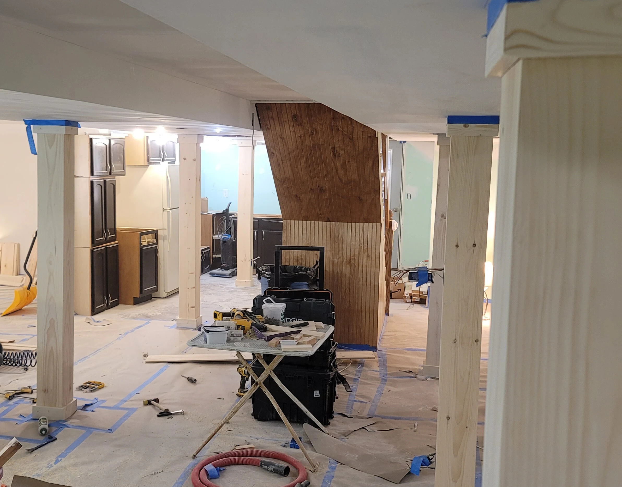 Basement mid-framing, with a plywood accent wall under construction and cabinets in place