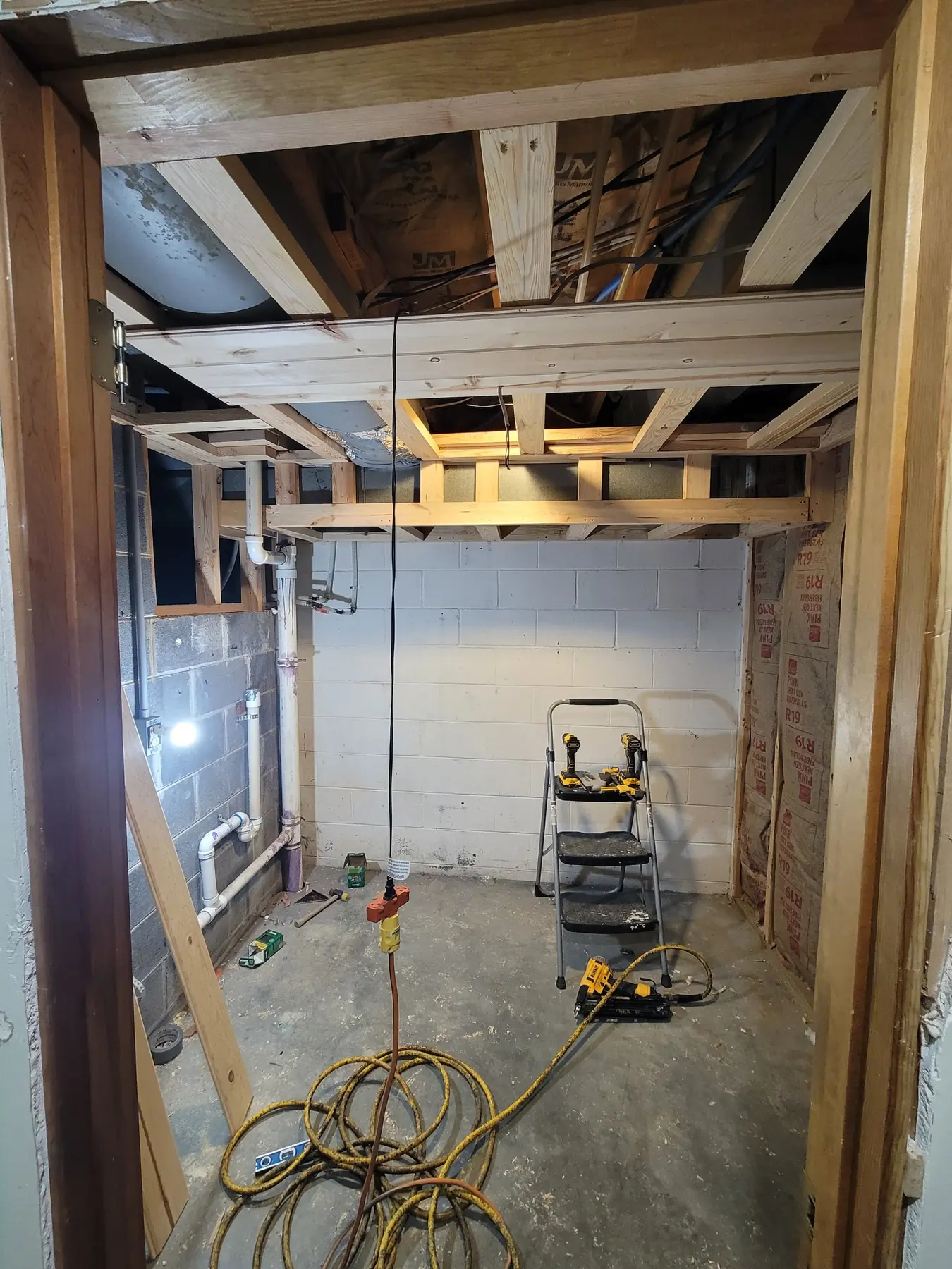 Ceiling framing built around the ductwork, with tongue-and-groove pine partly installed and the block walls still bare