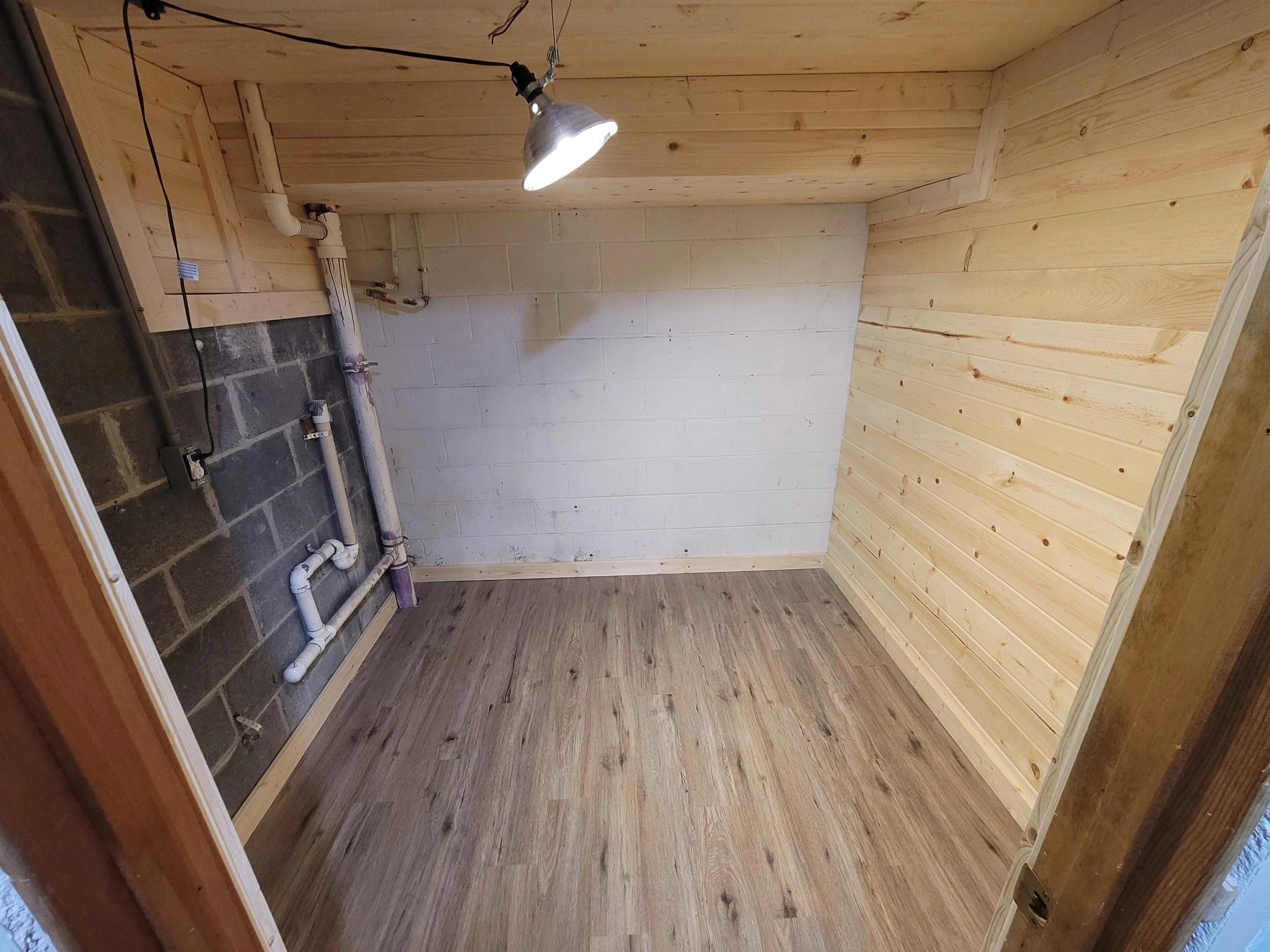 Finished tongue-and-groove pine utility nook with vinyl plank floor