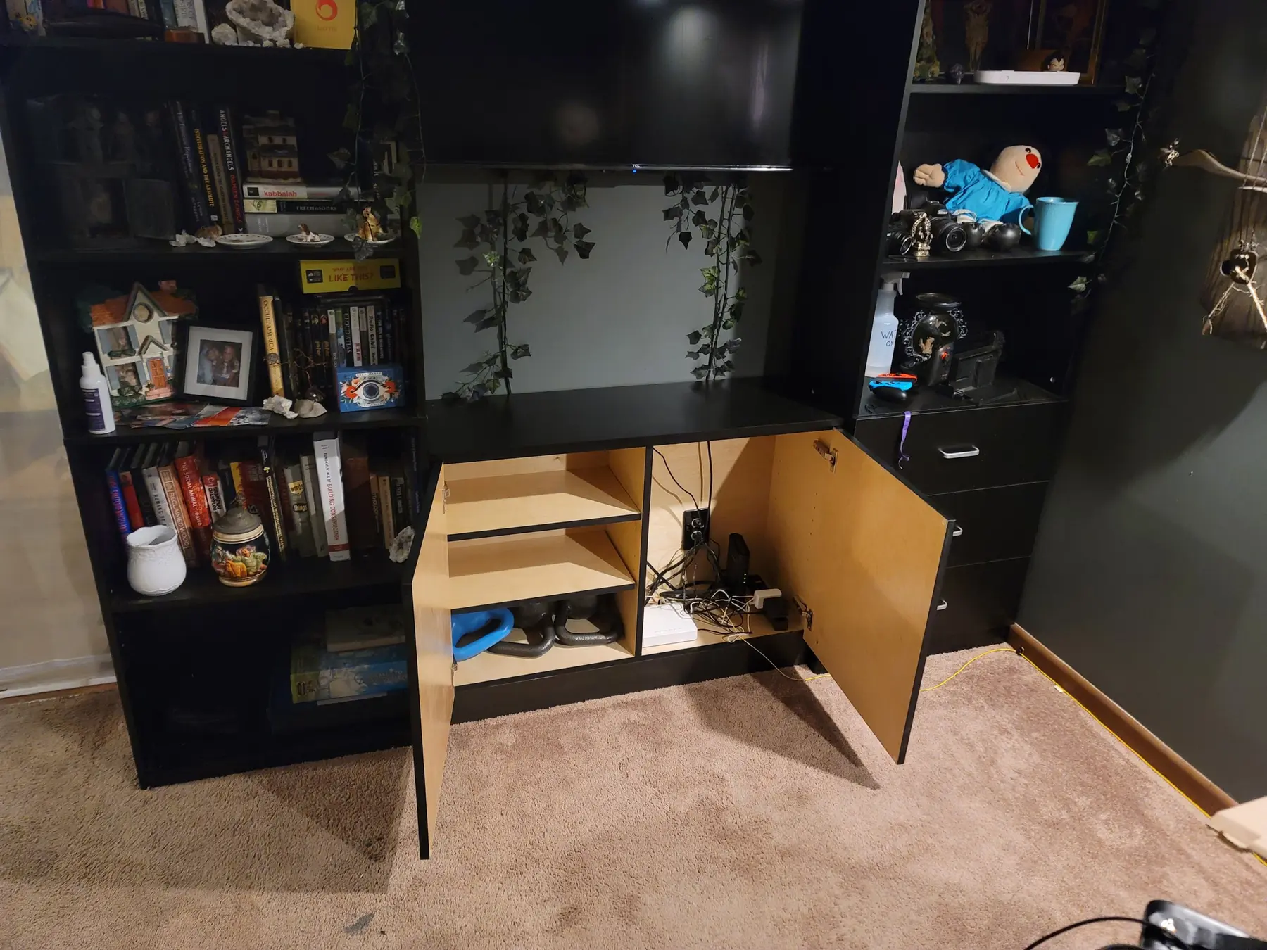 Built-in media cabinet lower doors open showing interior shelving and cable routing